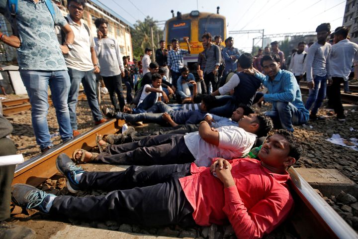 Job seekers lie on railway tracks as they block train services during a protest demanding recruitment into the railway services in Mumbai on March 20, 2018. 