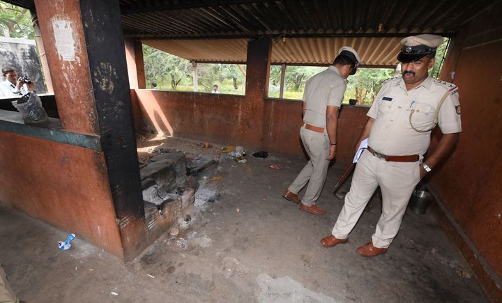 Policeman inspect the kitchen of a temple after a case of suspected food poisoning in Sulawadi village in Chamarajnagar district of Karnataka, Dec. 15, 2018.