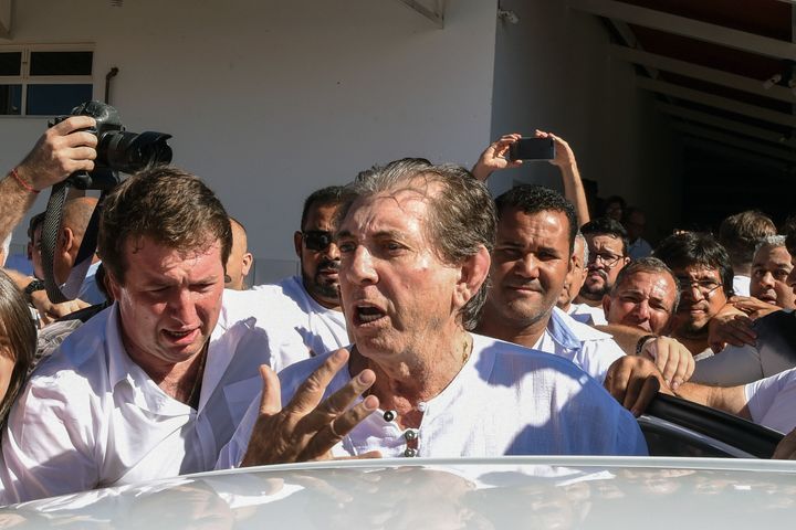 João Teixeira de Faria (center), known as “João de Deus,” or John of God, is escorted by supporters as he arrives at his “healing center” Abadiania, Brazil, on Dec. 12.