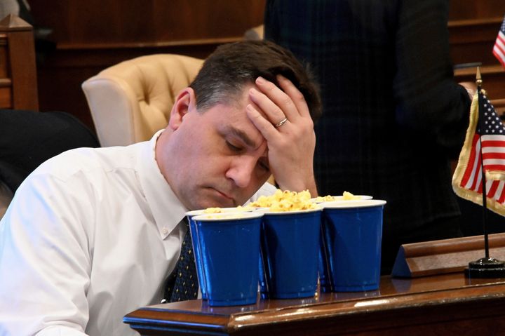 Michigan Sen. Pat Colbeck (R-Canton) is stocked up with popcorn, but holds his head in his hands, facing a long night at the Michigan senate on Dec. 20, 2018.