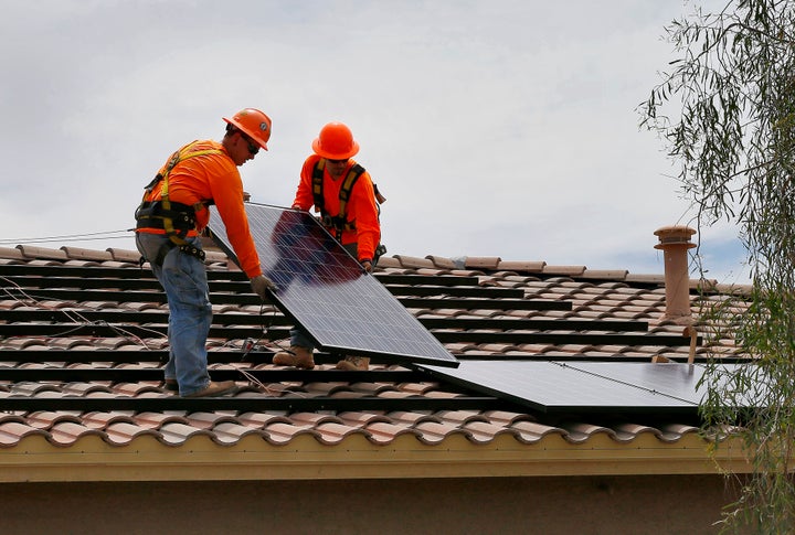 electricians Adam Hall, right, and Steven Gabert, install solar panels on a roof for Arizona Public Service company in Goodyear, Arizona. 