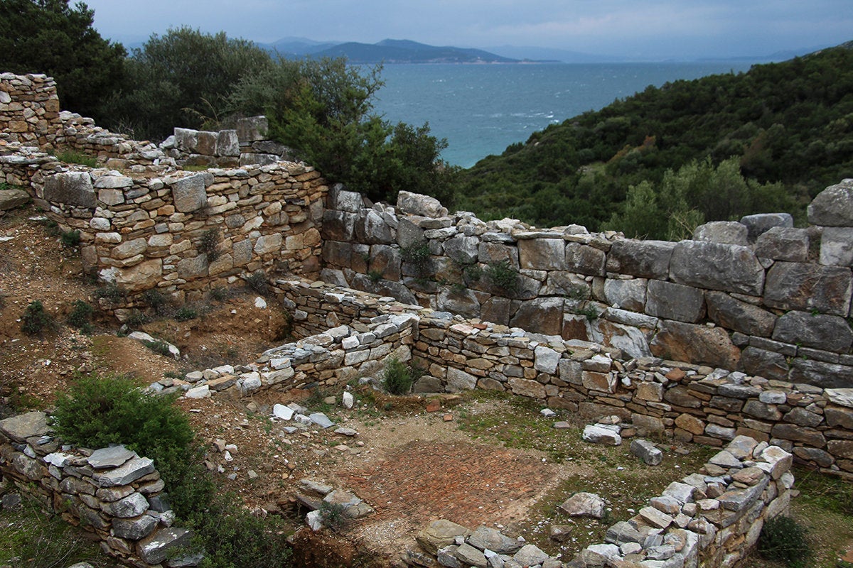 Ερείπια σπιτιών με απλούς τοίχους και τμήμα του ισχυρούτείχους με μεγάλες, καλοκτισμένες πέτρες. 