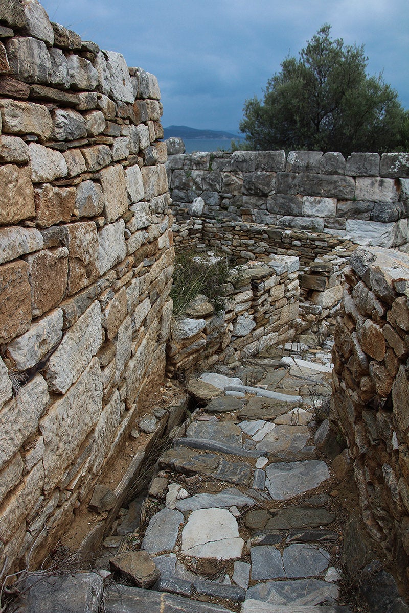 Δρομάκι που ένωνε την κεντρική οδό με την Ανατολική Πύλη-λιθόστρωτο, με ανοικτό αγωγό για την παροχέτευση των ομβρίωνυδάτων. 