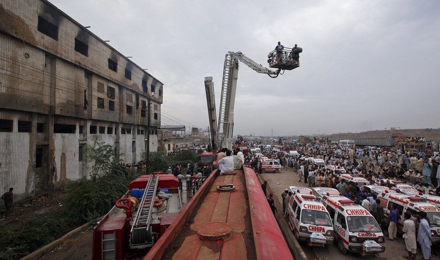 Nach dem Inferno: Am Tag nach der Brandkatastrophe ist die Straße vor der Fabrik am Rande eines Industriegebiets von Karachi voller Einsatzkräfte.