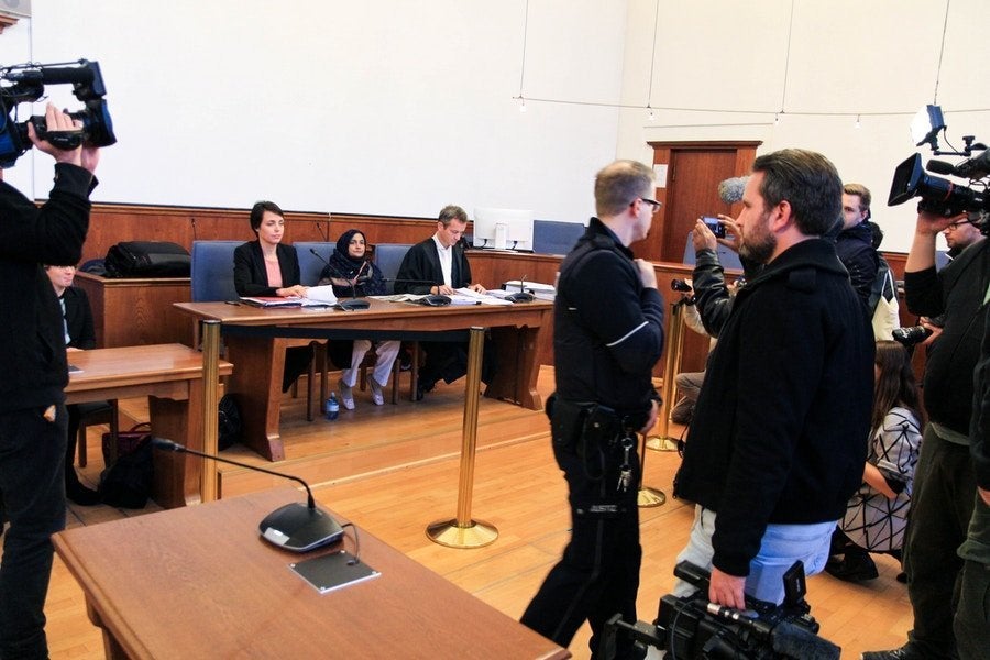 Großes Interesse: Als ECCHR-Juristin Miriam Saage-Maaß, Klägerin Saeeda Khatoon und Rechtsanwalt Remo Klinger (v. l. n. r.) im Gerichtssaal Platz nehmen, sind bereits geschätzte 40 Journalisten vor Ort.