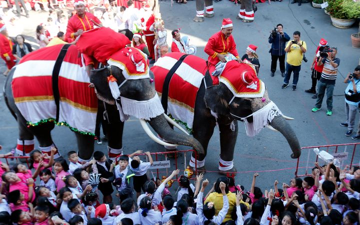 Elephants in Santa Claus costumes perform for students during Christmas celebrations at the Jirasart school in Bangkok, Thailand.