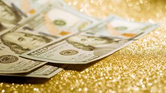 Saving Huffpost - the dollars banknotes on gold glitter background represent the concept of wealth and investment success