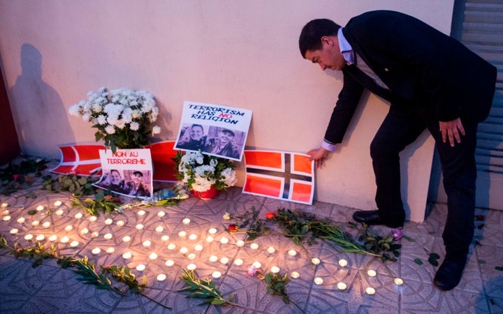 A Moroccan man places a Norwegian flag next to flowers and the portraits of murdered Danish student Louisa Vesterager Jespersen and Norwegian Maren Ueland, in the Moroccan central city of Marrakesh on December 21.