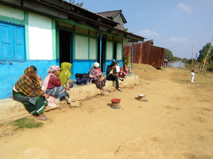 Melambok and Dimonme’s mother, Jostina Dkhar (in the green shawl) sits on the verandah of the family’s home.