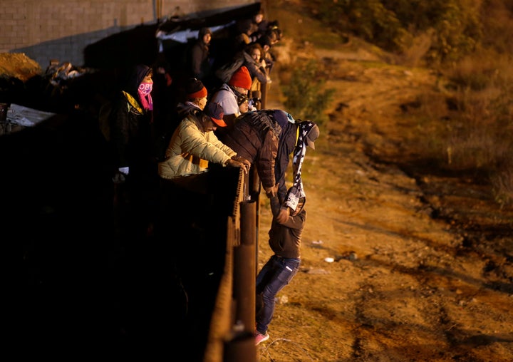 A migrant from Honduras, part of a caravan of thousands of Central Americans, jumps from the border fence to cross into the U