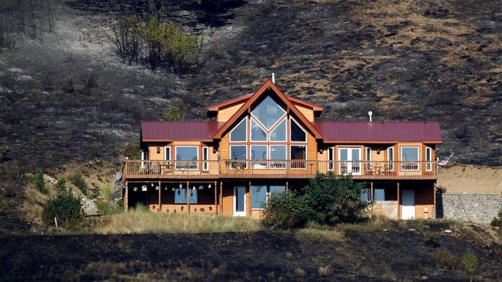 A house stands after surviving a wildfire near Cle Elum, Washington. The house had defensible space around the structure, such as a lack of trees and brush up against the house, preventing flames from reaching it. 