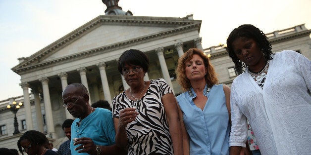 COLUMBIA, SC - JUNE 23: Participants link arms during a moment of silence at a memorial service for the nine victims of last week's shooting at Emanuel African Methodist Episcopal Church organized by students from the University of South Carolina and South Carolina State University on the grounds of the South Carolina State House June 23, 2015 in Columbia, South Carolina. South Carolina governor Nikki Haley asked that the flag be removed after debate over the flag flying on the capitol grounds was kicked off after nine people were shot and killed during a prayer meeting at the Emanuel African Methodist Episcopal Church in Charleston, South Carolina. (Photo by Win McNamee/Getty Images)