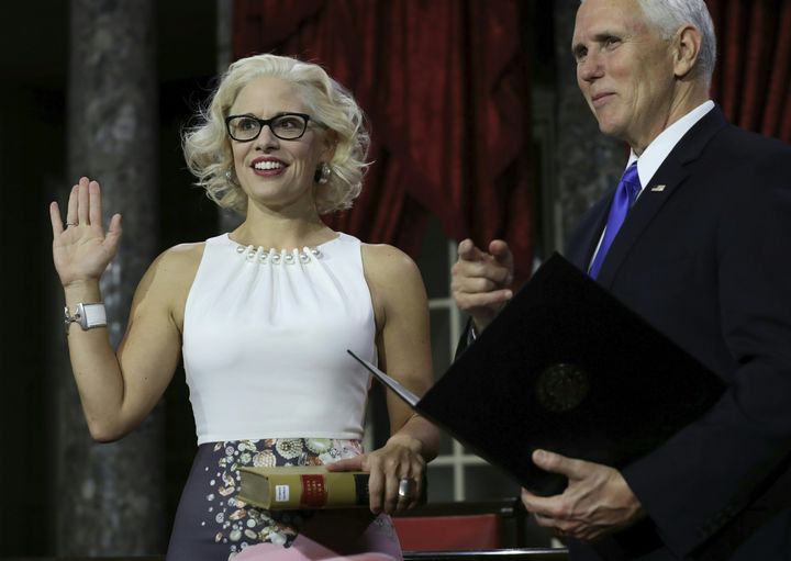 Sen. Kyrsten Sinema (D-Ariz.) holds a law book as she is sworn in by Vice President Mike Pence on Jan. 3 during the swearing-