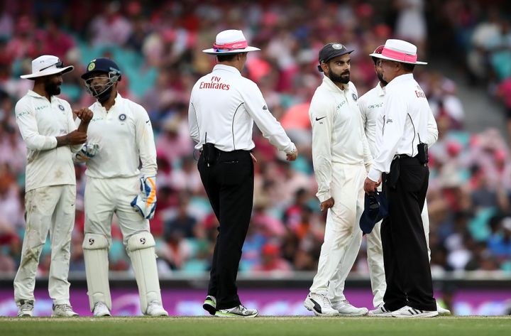 Virat Kohli of India speaks to the umpires as bad light stopped play during day three of the Fourth Test match in the series between Australia and India at Sydney