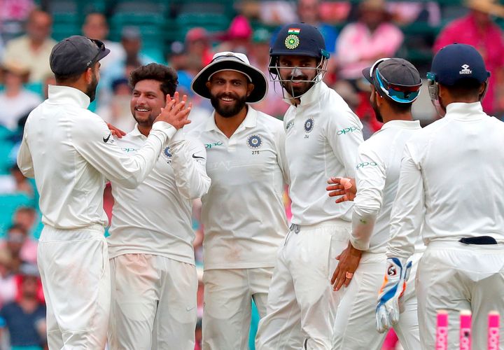 Kuldeep Yadav (2nd L) celebrates with captain Virat Kohli (L) and teammates after dismissing Australia's captain Tim Paine during the third day's play of the fourth and final cricket Test between India and Australia