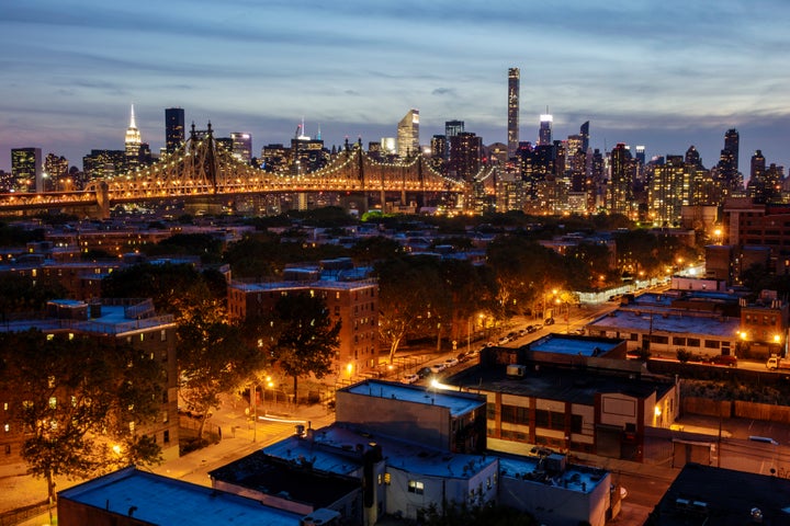 The Manhattan skyline glowing with electric power, as seen from the Long Island City side of the Queensboro Bridge.