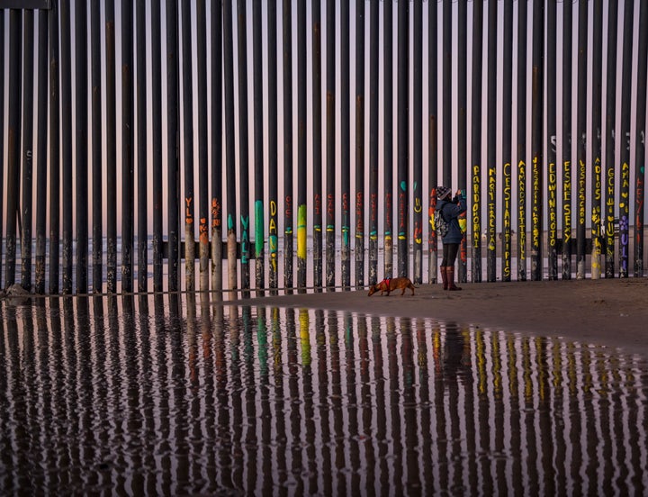 A woman takes a snapshot by the border fence between San Diego and Tijuana, as seen from Mexico, on Thursday.