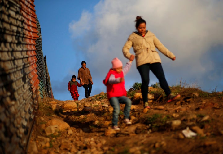 Migrants from Honduras, part of a caravan of thousands from Central America trying to reach the United States, walk next to the border fence as they prepare to cross it illegally, in Tijuana, Mexico, on Dec. 27.