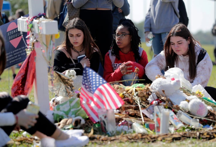 Students sit at a makeshift memorial for one of the victims of the mass shooting at Marjory Stoneman Douglas High School, Mar