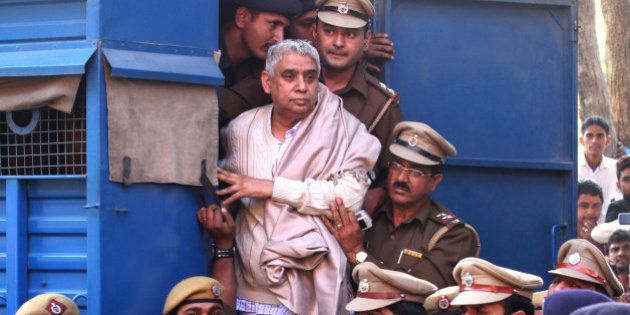 Controversial religious leader Sant Rampal stands by the door of a police van as he is brought to a court, surrounded by police personnel in Chandigarh, India, Thursday, Nov. 20, 2014. Indian police arrested the 63-year-old self-styled Hindu guru at his sprawling ashram in the northern part of the country, ending a days-long standoff in which six people died and hundreds were injured. He is wanted for questioning in a 2006 murder case, but has repeatedly ignored orders to appear in court. (AP Photo/Kapil Sethi)
