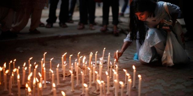 An activist places a candle on a pavement during a candle lit vigil to protest against the gang rape...