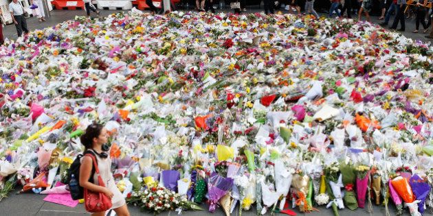 SYDNEY, AUSTRALIA - DECEMBER 16: A woman walks past flowers placed by people as a mark of respect for the victims of Martin Place siege on December 16, 2014 in Sydney, Australia. Sydney siege gunman Man Haron Monis, was shot dead by police in the early hours of Tuesday morning after taking hostages at the Lindt Chocolat Cafe in Martin Place. Two other people died, 33-year-old cafe manager Tori Johnson and 38-year-old Sydney barrister Katrina Dawson. Six people have been injured and have been taken to hospital. (Photo by Daniel Munoz/Getty Images)