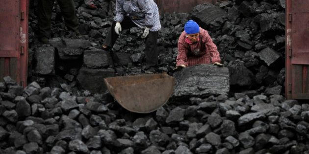 In this Nov. 27, 2014 photo, workers load coal from a truck to a process station in Tangxian in China's Hebei province. Just a few dozen miles from the capital of Beijing, in Hebei province, coal use has long been a way of life here, with countless house-sized mounds of it dotting the forest floor. Yet the soot-covered residents of Tang County said they see change coming as Chinese leaders pledge to cut back on the kind of rampant coal use that has made this country the worldâs biggest emitter of greenhouse gases. (AP Photo/Andy Wong)