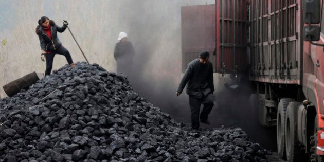 In this Nov. 27, 2014 photo, workers load coal from a truck at a process station for sale in Tangxian in China's Hebei province. Just a few dozen miles from the capital of Beijing, in Hebei province, coal use has long been a way of life here, with countless house-sized mounds of it dotting the forest floor. Yet the soot-covered residents of Tang County said they see change coming as Chinese leaders pledge to cut back on the kind of rampant coal use that has made this country the worldâs biggest emitter of greenhouse gases. (AP Photo/Andy Wong)