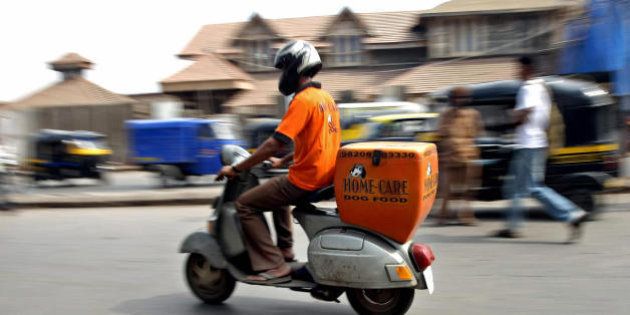 TO GO WITH LIFESTYLE-INDIA-ANIMALS-FOOD,FEATURE BY PHIL HAZLEWOOD A Home-Care Dog Food delivery boy rides his scooter as he delivers meals to clients in Mumbai on January 24, 2009. Wasiff Khan has an admission: he used to be scared of dogs. That's not unusual in Mumbai, where strays can have a bite worse than their bark. But Khan runs a deluxe dogfood delivery service, with the pets of Bollywood A-listers and top executives among his select clientele. Just like Mumbai's army of 'dabbawallahs' who deliver tiffin boxes of home-cooked food to hungry humans, uniformed Homecare Dogfood drivers criss-cross the city every morning with speciality meals for man's best friend. AFP PHOTO/ Pal PILLAI (Photo credit should read PAL PILLAI/AFP/Getty Images)
