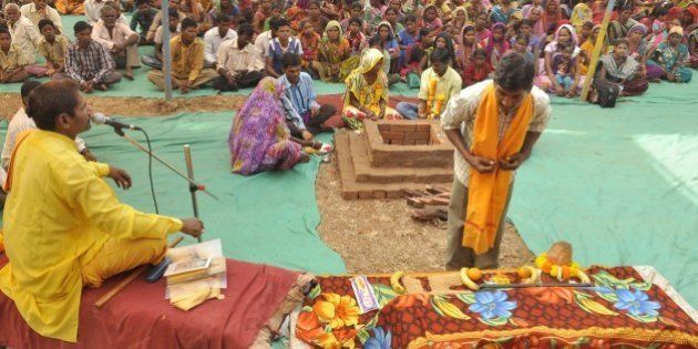 An Indian tribesperson (R, foreground) participates in a conversion ritual of some 200 Christians into Hinduism, at Aranai Village in Valsad district of Gujarat state, some 350 kms from Ahmedabad, on December 20, 2014. Hardline Hindu groups came under fire December 21 after some 200 Christians were converted in the Indian prime minister's home state, amid increasing concern at the right-wing government's perceived pro-Hindu tilt. AFP PHOTO / STR (Photo credit should read STRDEL/AFP/Getty Images)
