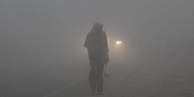 JAMMU, INDIA - DECEMBER 18: A man wrapped in warm clothes, moved through a fog covered road during a cold and foggy morning on December 18, 2014 in Jammu, India. Fog and mist continued to affect normal life and vehicular traffic across the state despite the mercury rose to one to two degree C at many places last night, the official said. The MeT department has forecast fresh Western Disturbance (WD) would affect the state from tomorrow resulting into rainfall or snowfall at few places. (Photo by Nitin Kanotra/Hindustan Times via Getty Images)