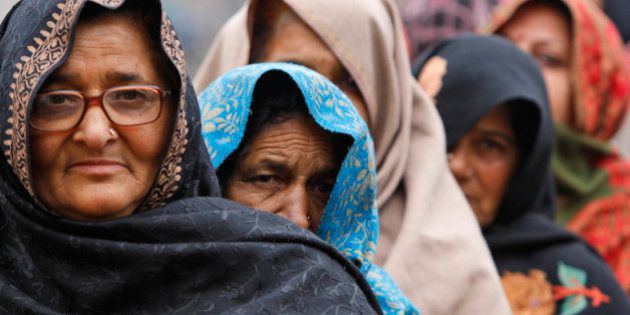 Indian women, wrapped in shawls to keep warm, stand in a queue to cast their votes outside a polling station during the fifth phase of voting, at Satrayan village near the India-Pakistan international border, about 32 kilometers from Jammu, India, Saturday, Dec. 20, 2014. The fifth and last stage of polling is being held in Jammu and Kashmir state and Jharkhand. (AP Photo/Channi Anand)