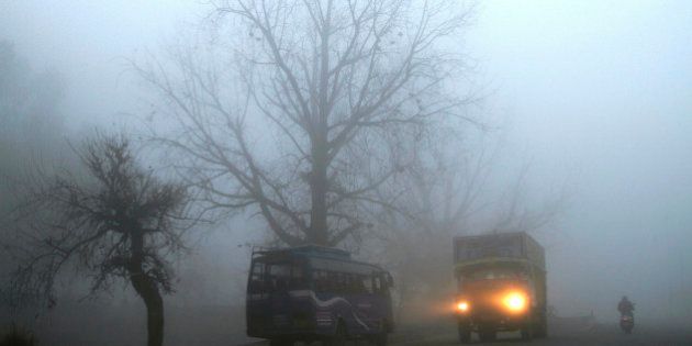 A truck passes amid morning fog on a national highway, near Jammu, India, Friday, Jan. 31, 2014. Dense fog enveloped most part of northern India disrupting rail, road and air traffic as cold conditions continue unabated, according to local reports. (AP Photo/Channi Anand)