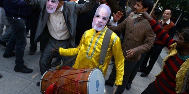 A traditional drummer wears a mask bearing the portrait of Indian Prime Minister Narendra Modi as Bharatiya Janata Party (BJP) supporters celebrate following the Jharkhand, and Jammu and Kashmir state assembly election results in New Delhi on December 23, 2014. Indian Prime Minister Narendra Modi's Hindu nationalist party made significant election gains in the restive Muslim-majority state of Jammu and Kashmir but will fall well short of a majority, according to partial results out December 23. AFP PHOTO / CHANDAN KHANNA (Photo credit should read Chandan Khanna/AFP/Getty Images)
