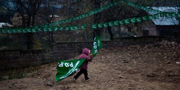 KOLGOM, KASHMIR, INDIA - NOVEMBER 27: A child carrries a PDP flag during campaign rally for Mufti Mohammad Sayeed, former Chief Minister of Indian administered Kashmir and patron of Kashmir's main opposition political party, the Jammu and Kashmir People's Democratic Party (PDP), on November 27, 2014, in Kolgom south of Srinagar, the summer capital of Indian administered Kashmir, India. Amid tight security, Kashmiris will cast their votes in the second phase of assembly elections in the strife torn Jammu and Kashmir, even as most pro-independence groups have asked people to boycott the five phased polls which will end on December 20 and the results would be announced on December 23 (Photo by Yawar Nazir/Getty Images