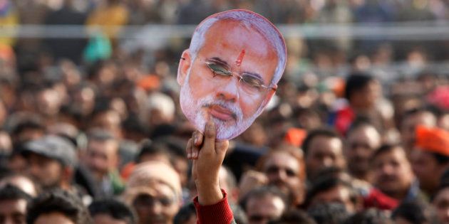 A supporter of India's ruling Bharatiya Janata Party (BJP) holds up a mask of Prime Minister Narendra Modi during an election campaign rally in Kathua, about 90 kilometers from Jammu, India, Saturday, Dec.13, 2014. The final two phases of the five-phased state elections of Jammu and Kashmir will be held on Dec. 14 and 20. (AP Photo/Channi Anand)