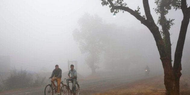 Indian villagers cycle amidst fog early morning in Allahabad, India, Friday, Dec. 5, 2014. Several parts of north India are experiencing cold weather conditions. (AP Photo/Rajesh Kumar Singh)