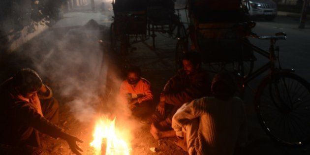 Indian rickshaw pullers warm themselves beside a fire on a pavement in Jalpaiguri on December 28, 2014. Many parts of northern India are experiencing dense foggy cold days with the resulting low visibility affecting road, rail and air traffic. AFP PHOTO/Diptendu DUTTA (Photo credit should read DIPTENDU DUTTA/AFP/Getty Images)