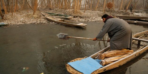 A Kashmiri boat man breaks the frozen surface of water of a Lake on a cold and foggy morning in Srinagar, in India, Thursday, Dec. 25, 2014. Cold wave tightened its grip on the Kashmir valley as it continues to reel under intense cold wave for the past few days with widespread snowfall in the hilly areas. (AP Photo/Mukhtar Khan)