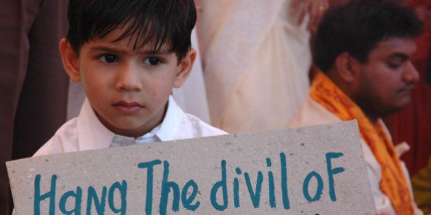 A boy holds a placard as he attends a prayer for world peace at a school in Ahmadabad, India, Friday, Feb. 16, 2006. The placard refers to the Nithari killing case where a businessman Moninder Singh Pandher and his servant Surender Kohli are charged of the death of up to 38 women and children after the victims were kidnapped and raped. (AP Photo/Ajit Solanki)
