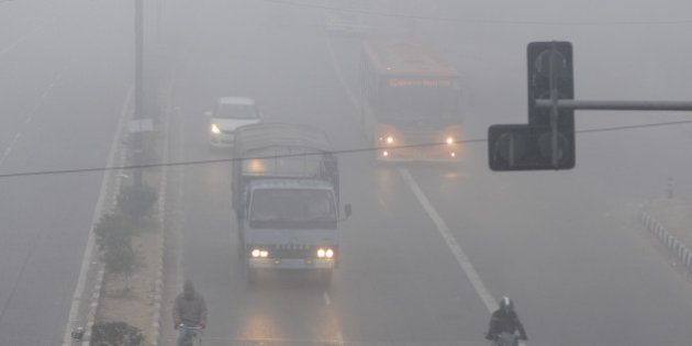 NEW DELHI, INDIA - DECEMBER 29: People commute amidst dense fog on a cold morning on December 29, 2014 in New Delhi, India. It was a chilly morning with minimum temperature settling three notches below normal at 4.8 degrees Celsius while dense fog enveloped the city, delaying 98 trains and several flights. (Photo by Sushil Kumar/Hindustan Times via Getty Images)
