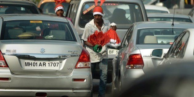 Indian street vendors carry Christmas ornaments and paraphernalia for sale as they walk in traffic in Mumbai on December 24, 2014. Despite Christians forming a little over two percent of the billion plus population in India, with Hindus comprising the majority, Christmas is celebrated with fanfare and zeal throughout the country. AFP PHOTO/ PUNIT PARANJPE (Photo credit should read PUNIT PARANJPE/AFP/Getty Images)