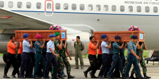 Indonesian soldiers carry coffins containing bodies of victims of AirAsia Flight 8501 upon arrival at Indonesian Military Air Force base in Surabaya, Indonesia, Wednesday, Dec. 31, 2014. A massive hunt for the victims of the jet resumed in the Java Sea on Wednesday, but wind, strong currents and high surf hampered recovery efforts as distraught family members anxiously waited to identify their loved ones. (AP Photo/Firdia Lisnawati)