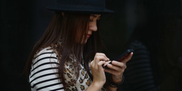 A woman uses a mobile devices on a street in Shanghai on September 25, 2013. China will open its first free trade zone in an ambitious effort to transform its commercial centre into a global hub with Hong Kong's South China Morning Post reporting that the zone will even allow access to Facebook, Twitter and other websites banned nationwide by China's censorship authorities who strictly control online content for fear of political and social unrest. AFP PHOTO/Peter PARKS (Photo credit should read PETER PARKS/AFP/Getty Images)