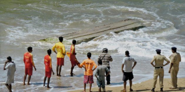 Rescue workers and policemen stand near a boat that capsized, on a beach in Panaji, on the southern coast of Goa state, India, Tuesday, Oct. 28, 2014. The boat taking tourists on a dolphin-sighting trip capsized off India's west coast Tuesday, killing three Russian women, police said. The women were among 10 Russian tourists who chartered the motorboat to follow dolphins more than a kilometer (half mile) off popular Betul beach. A large wave toppled the boat, trapping some of the passengers underneath, police official Nilesh Shirotkar said. (AP Photo/Press Trust of India)