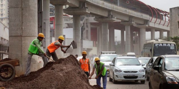 Workers labor at the roadside below an elevated track, operated by Rapid MetroRail Gurgaon Ltd., near DLF Cybercity in Gurgaon, India, on Wednesday, March 26, 2014. Indian stocks rose, sending the benchmark index to a record, after the rupee rose to an eight-month high and sovereign bonds gained on speculation the worlds largest democracy will elect a government capable of reviving economic growth. Photographer: Kuni Takahashi/Bloomberg via Getty Images