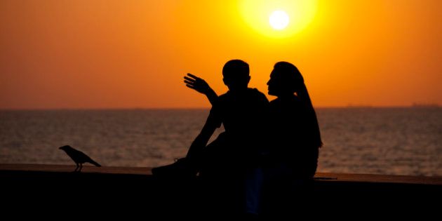 INDIA - MARCH 20: Young Indian couple sit on seawall at sunset at Nariman Point, Mumbai, formerly Bombay, India (Photo by Tim Graham/Getty Images)