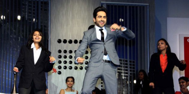 Indian Bollywood actors Ayushmann Khurrana (C) and Sonam Kapoor (2nd L, background) participate in a promotional event for the forthcoming Hindi film 'Bewakoofiyaan' in Mumbai on March 12, 2014. AFP PHOTO/STR (Photo credit should read STRDEL/AFP/Getty Images)