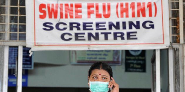 An Indian woman, wearing a mask, talks on her mobile phone outside the H1N1 swine flu screening centre at the Government Gandhi Hospital in Hyderabad on August 7, 2010. Health authorities confirmed that 15 more persons have tested positive for Swine Flu in the twin cities area of Hyderabad, local reports said. Six out of 21 nurses admitted to the hospital have tested positive for H1N1. AFP PHOTO/Noah SEELAM (Photo credit should read NOAH SEELAM/AFP/Getty Images)