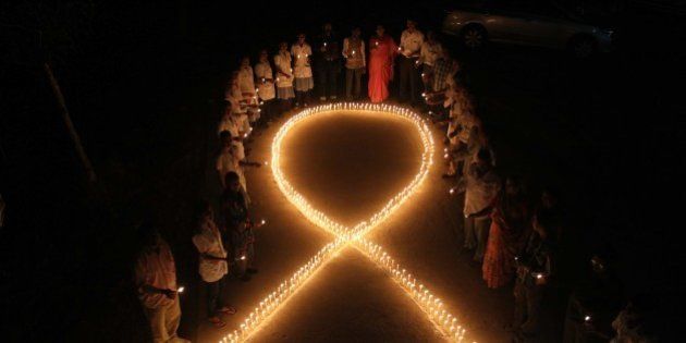 Indian nursing students and medical staff hold candles and stand by a formation in the shape of a red ribbon, the universal symbol of awareness and support for those living with HIV, made with candles in Sanand near Ahmadabad, India, Saturday, Nov. 30, 2013. (AP Photo/Ajit Solanki)